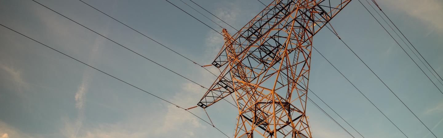 Photograph of a power line tower with the sky in the background 