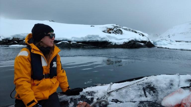 Emily Moberg sits on the edge of a boat while doing field research in a snowy climate.