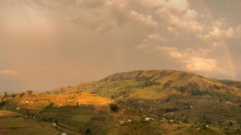 Hill in Uganda with rainbow across sky