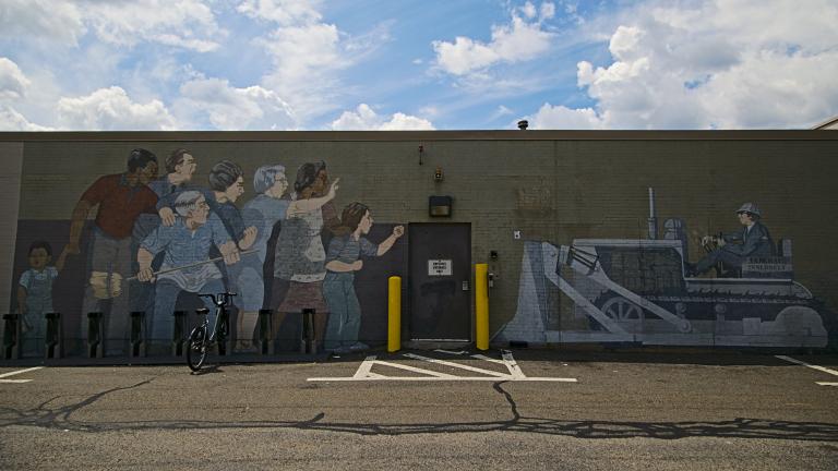 A photo of a mural depicting a group of people standing in front of a bulldozer. The bulldozer reads "Federal Inner Belt I-95."