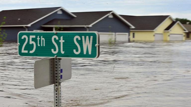 A street sign and houses are underwater due to flooding.