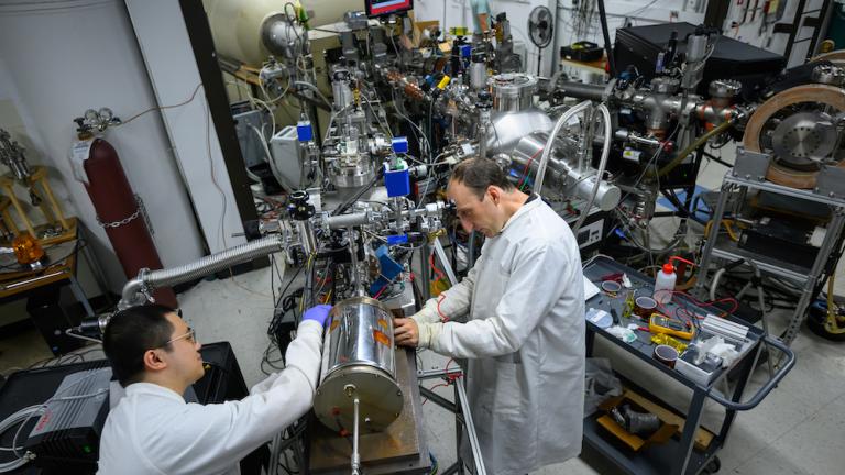 Postdoc Weiyue Zhou (left) and Associate Professor Michael Short attach a novel test chamber containing a metal sample and salt to the end of a proton accelerator. Experiments to date show that proton irradiation decreases the rate of corrosion in certain metal alloys — potentially good news for designers of promising nuclear power reactors that rely on molten salts, which tend to be highly corrosive. 