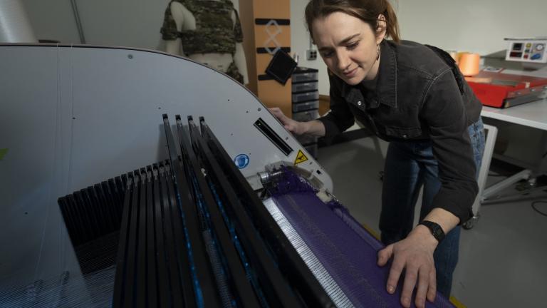 At Lincoln Laboratory’s Defense Fabric Discovery Center, Erin Doran demonstrates how reflective fibers can be woven into textiles. Such fibers could function as indelible, scannable labels to easily sort fabrics for recycling. 