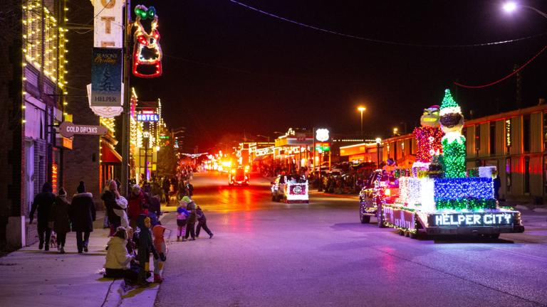 Residents and visitors watch as the city float drives by in the annual light parade in Helper, Utah.