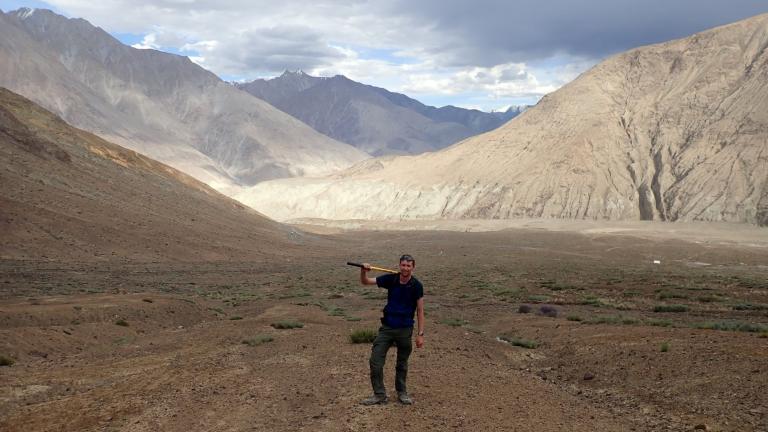 Craig Martin holds a pickaxe in the Himalayan mountains.