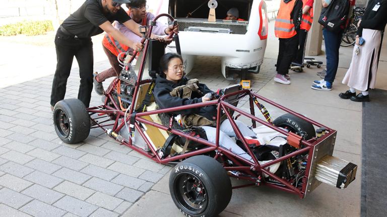 Students help the MIT Motorsports team push their car into Lobby 13 for the 2024 MIT Edgerton Center student showcase. 