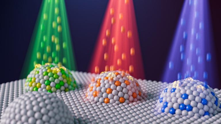 Artist’s representation of nanoparticles with different compositions created by combining two techniques: metal exsolution and ion irradiation. The different colors represent different elements, such as nickel, that can be implanted into an exsolved metal particle to tailor the particle’s compositions and reactivity.