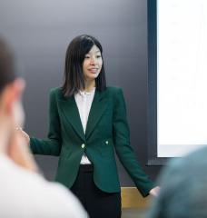 Jing Li, an assistant professor of applied economics, engages with her students during the Electricity Strategy Game debrief.