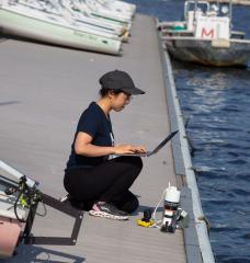 Charlene Xia, pictured at the MIT Sailing Pavilion, tests her microbiome monitoring system in the Charles River.