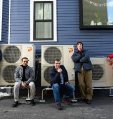 A modeling study by an MIT team has shown that electrifying residential heating can be a substantial step toward reducing carbon emissions, as well as costs, over the combined electricity and natural gas sectors. Here, the team poses beside a high-efficiency electric heat pump system that provides heating to the home, replacing the natural gas-fired furnace. Left to right: Audun Botterud, Saurabh Amin, Rahman Khorramfar, Morgan Santoni-Colvin, and Leslie Norford. Not pictured: Dharik Mallapragada.