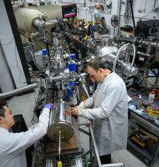 Postdoc Weiyue Zhou (left) and Associate Professor Michael Short attach a novel test chamber containing a metal sample and salt to the end of a proton accelerator. Experiments to date show that proton irradiation decreases the rate of corrosion in certain metal alloys — potentially good news for designers of promising nuclear power reactors that rely on molten salts, which tend to be highly corrosive. 