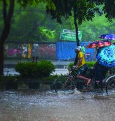 Man pedals rickshaw with passengers in heavy rain and flooded street 